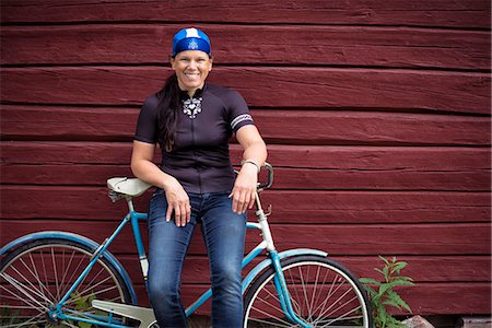 Portrait of mid-adult woman sitting on bicycle Stock Photo - Premium Royalty-Free, Code: 6102-08520523