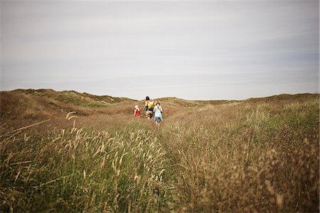 simsearch:6102-08761638,k - Mother with two daughters walking though meadow Foto de stock - Royalty Free Premium, Número: 6102-08521159