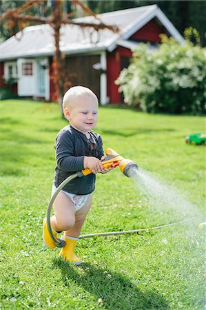 rubber boots grass - Boy with garden hose Stock Photo - Premium Royalty-Free, Code: 6102-08521204