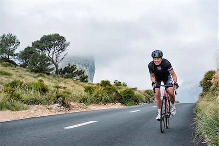 Woman cycling on country road Stock Photo - Premium Royalty-Free, Code: 6102-08642115