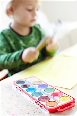 Boy painting, watercolor paints in foreground Stock Photo - Premium Royalty-Free, Code: 6102-08746345