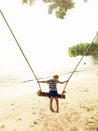 photos beach boys in asia - Boy swinging on beach Stock Photo - Premium Royalty-Free, Code: 6102-08746380