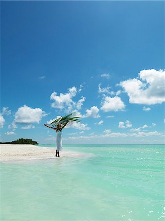 Woman holding palm leaf on tropical beach Foto de stock - Royalty Free Premium, Número: 6102-08746398