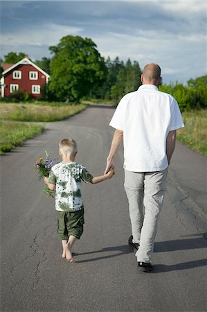 simsearch:6102-08761067,k - Father walking with son on road, boy holding flowers Fotografie stock - Premium Royalty-Free, Codice: 6102-08746490