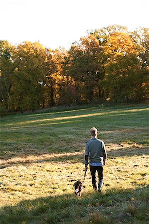 simsearch:6102-08748643,k - Man walking dog Foto de stock - Royalty Free Premium, Número: 6102-08746428