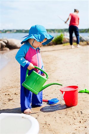 Boy playing with watering can on beach Stock Photo - Premium Royalty-Free, Code: 6102-08746431