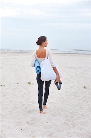 simsearch:6102-08747075,k - Young woman with exercise mat standing on beach Stock Photo - Premium Royalty-Free, Code: 6102-08746900