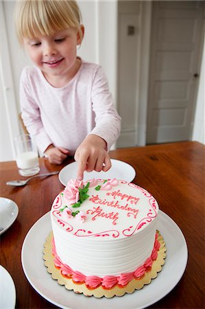 Girl touching birthday cake Stock Photo - Premium Royalty-Free, Code: 6102-08748482