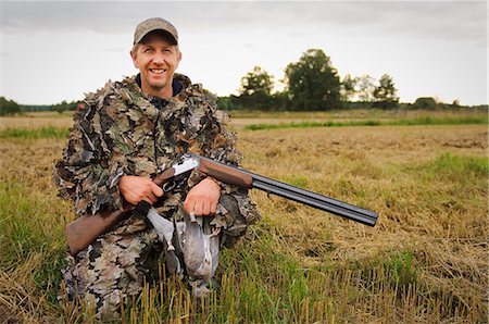 pigeon white - Hunter holding pigeon and rifle, smiling, portrait Stock Photo - Premium Royalty-Free, Code: 6102-08748573