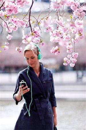 simsearch:6102-03750096,k - Young woman with mp3 player near cherry blossom trees Stock Photo - Premium Royalty-Free, Code: 6102-08760306