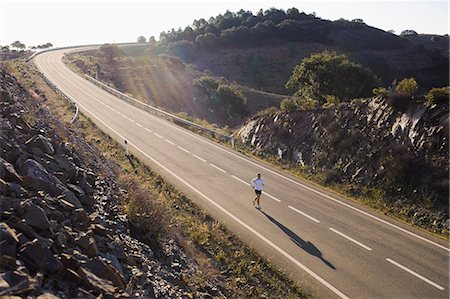 Runner running on road, high angle view Stock Photo - Premium Royalty-Free, Code: 6102-08760956