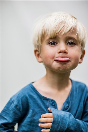 Portrait of boy sticking out tongue, studio shot Stock Photo - Premium Royalty-Free, Code: 6102-08761270