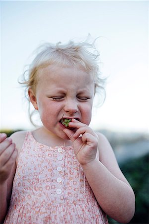 Girl making face while eating strawberry Photographie de stock - Premium Libres de Droits, Code: 6102-08858527