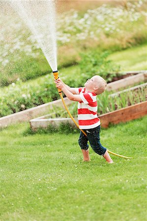 sandbox - Boy playing with garden hose Stock Photo - Premium Royalty-Free, Code: 6102-08881547