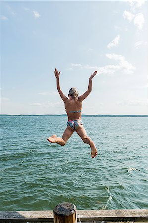 preteen girl swimsuit rear view - Woman jumping into sea Stock Photo - Premium Royalty-Free, Code: 6102-08881517