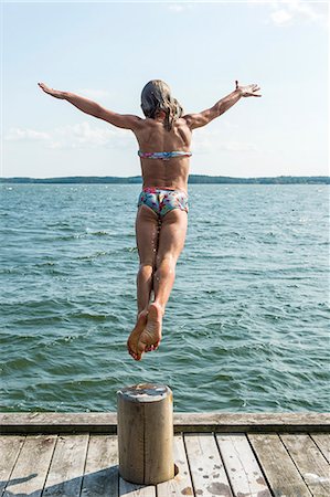 preteen girl swimsuit rear view - Woman jumping into sea Stock Photo - Premium Royalty-Free, Code: 6102-08881518