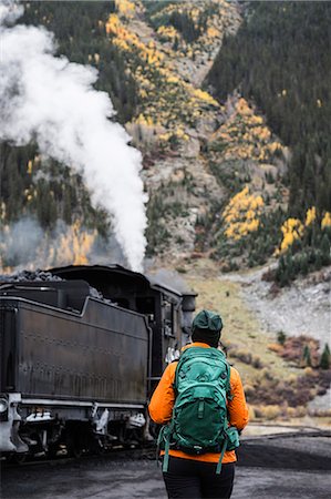 Tourist walking in mountain and looking at steam locomotive Stock Photo - Premium Royalty-Free, Code: 6102-08881908