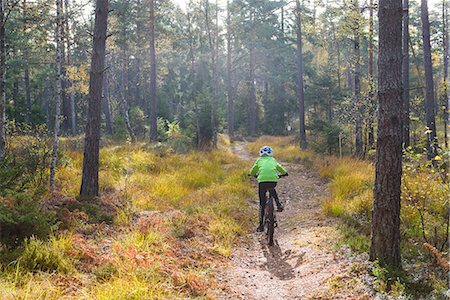 simsearch:6102-08995190,k - Boy cycling through forest Foto de stock - Sin royalties Premium, Código: 6102-08882356