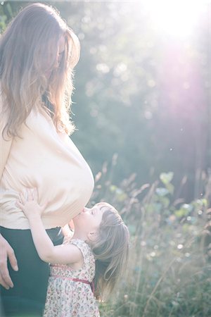 Girl kissing her mothers belly Photographie de stock - Premium Libres de Droits, Code: 6102-08885273