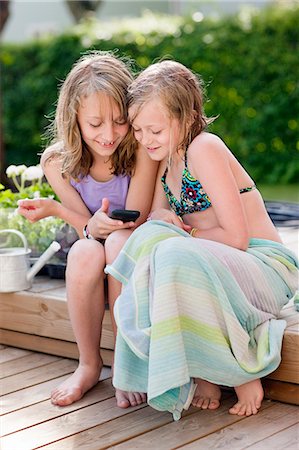 simsearch:6102-03905967,k - Two girls sitting in garden and texting on mobile phone Photographie de stock - Premium Libres de Droits, Code: 6102-08800208