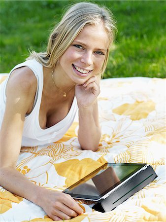 simsearch:6102-08746546,k - Young woman lying on blanket with digital tablet, smiling, portrait Photographie de stock - Premium Libres de Droits, Code: 6102-08800330