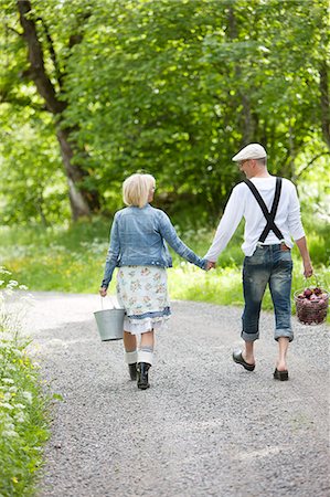 Mature couple holding hands and walking through graveled road Stock Photo - Premium Royalty-Free, Code: 6102-08800441