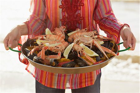 simsearch:6102-03859363,k - Woman on a beach with a plate of paella, Sweden. Foto de stock - Sin royalties Premium, Código: 6102-08800590