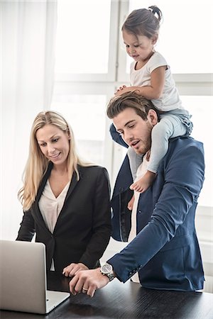 simsearch:6102-07768856,k - Father giving daughter piggyback and looking with woman at laptop Photographie de stock - Premium Libres de Droits, Code: 6102-08942242