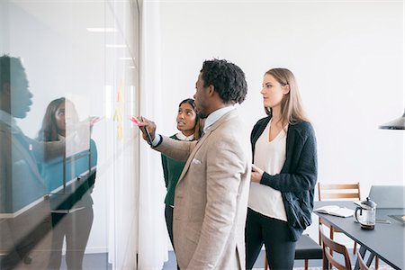 Man and women putting adhesive notes on glass Stock Photo - Premium Royalty-Free, Code: 6102-08942346