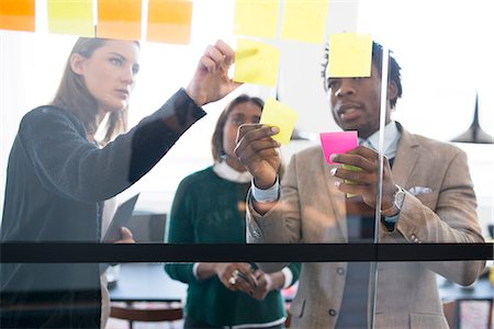 Man and women putting adhesive notes on glass Stock Photo - Premium Royalty-Free, Code: 6102-08942358