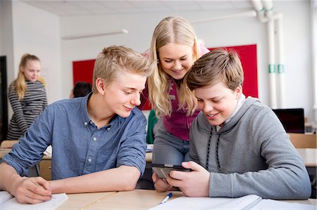 simsearch:6102-08951246,k - Teenagers looking at cell phone in classroom Fotografie stock - Premium Royalty-Free, Codice: 6102-08951207