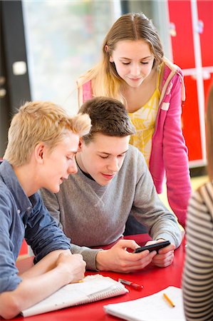 simsearch:6102-08951246,k - Teenagers looking at cell phone in classroom Fotografie stock - Premium Royalty-Free, Codice: 6102-08951204