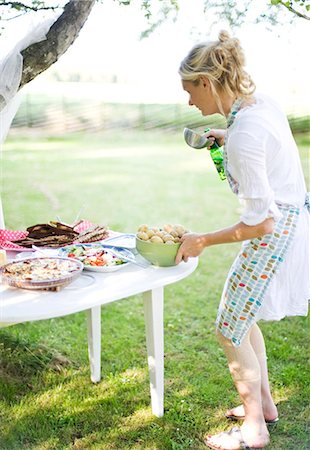 sommerparty - Woman putting food on table in garden Foto de stock - Sin royalties Premium, Código: 6102-08951848