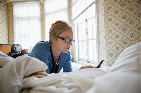 simsearch:6102-08881952,k - Woman using cell phone on bed Foto de stock - Sin royalties Premium, Código: 6102-08995097