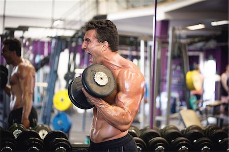simsearch:6102-08995506,k - Man exercising with dumbbells in gym Stock Photo - Premium Royalty-Free, Code: 6102-08995494
