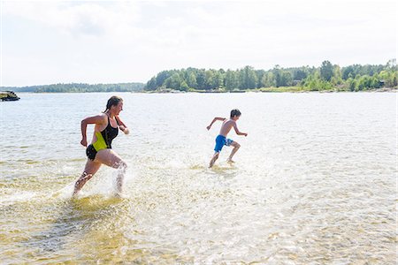 preadolescent bathing - Mother running with son in lake Photographie de stock - Premium Libres de Droits, Code: 6102-08995899