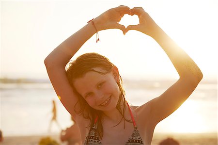 sign beach - Smiling girl making heart-shape with hands Stock Photo - Premium Royalty-Free, Code: 6102-08995993