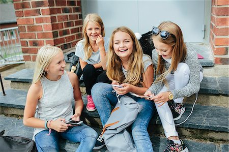 schoolyard - Girls sitting on steps and using cell phones Stock Photo - Premium Royalty-Free, Code: 6102-08996020