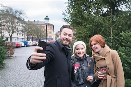 family smartphone in winter - Man with teenage girls taking selfie Stock Photo - Premium Royalty-Free, Code: 6102-08996262