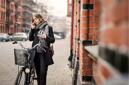 simsearch:6102-07768969,k - Young woman with bicycle on the phone Foto de stock - Royalty Free Premium, Número: 6102-08996375