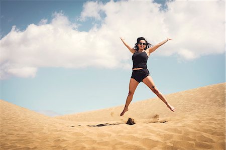 simsearch:6102-08566501,k - Woman jumping on sand dune Stock Photo - Premium Royalty-Free, Code: 6102-08996800