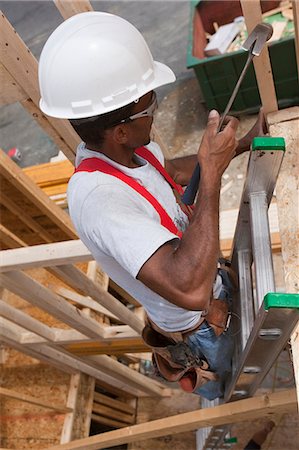 simsearch:6105-05396262,k - Hispanic carpenter using a hammer on a ladder at a house under construction Foto de stock - Royalty Free Premium, Número: 6105-05395991