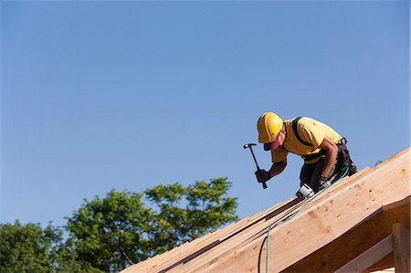 simsearch:6105-05396235,k - Carpenter hammering on roof rafters Foto de stock - Royalty Free Premium, Número: 6105-05396059