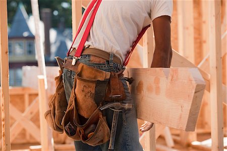 Mid section view of a carpenter carrying a wooden rafter Foto de stock - Sin royalties Premium, Código: 6105-05396065