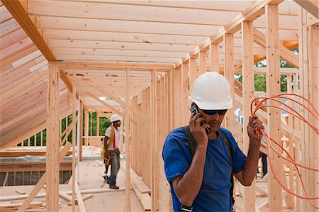 frame carpenters - Carpenter holding power cord and talking on mobile phone Stock Photo - Premium Royalty-Free, Code: 6105-05396077