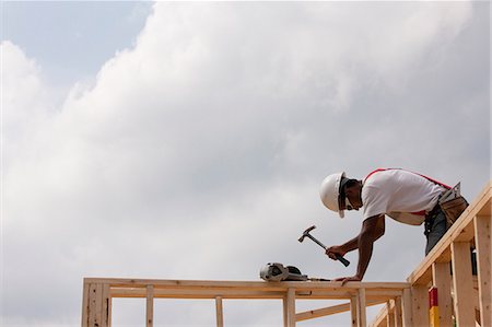 Low angle view of a carpenter hammering on wall frame Stock Photo - Premium Royalty-Free, Code: 6105-05396015