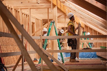 simsearch:6105-05396266,k - Hispanic carpenters bringing sheathing to roof at a house under construction Foto de stock - Royalty Free Premium, Número: 6105-05396163