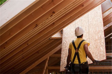 simsearch:6105-05396204,k - Hispanic carpenter pushing sheathing up to roof at a house under construction Stock Photo - Premium Royalty-Free, Code: 6105-05396181