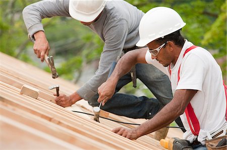 simsearch:6105-05396204,k - Hispanic carpenters using hammers on the roof of an under construction house Stock Photo - Premium Royalty-Free, Code: 6105-05396193