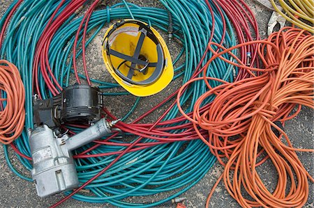 fio elétrico - Close-up of power cords and air hoses with a nail gun and a hardhat at a construction site Foto de stock - Royalty Free Premium, Número: 6105-05396191